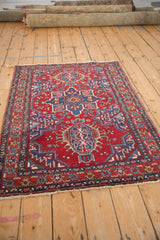 Vintage Karaja rug with a red field and geometric medallion, viewed from an angled perspective.