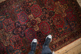 Antique Sarouk rug with raspberry red, navy, and gold inverted floral panel patterns.