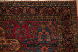 Antique Persian Sarouk rug with intricate borders, raspberry red and navy floral panels.