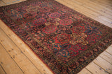 Antique Sarouk rug's raspberry red, navy, and gold floral panel design.