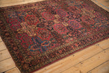 Antique Sarouk rug featuring raspberry red, navy floral panels, and a rich multi-toned border.