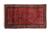Vintage Persian Lilihan rug with a floral pattern on a raspberry red field and sapphire blue border.