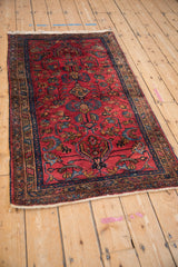 Angled view of a vintage Lilihan rug, showing its traditional floral pattern on a raspberry red field.