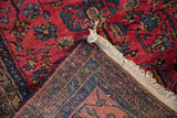 Folded corner of a vintage Lilihan rug showing the hand-knotted back and raspberry red pile.