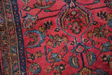 Detail of hand-knotted floral motifs in sapphire blue on a raspberry red vintage Lilihan rug.