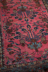 Detailed view of lustrous magenta pile and blue floral vine motifs.