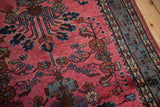 Vintage Lilihan rug's denim blue meandering vine border with raspberry red field.