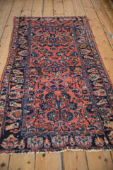 Angled view of a vintage Lilihan runner showing its dusty rose floral field and navy blue palmette border.