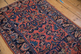 Angled view showing the varied pile texture and navy blue palmette border on a vintage Lilihan rug.