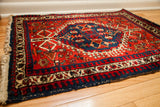 Bold red accent rug corner, featuring geometric patterns, deep navy border, and fringed edge.