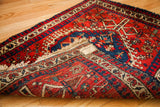 Northwest Persian rug corner reveals red patterns, blue border, and even woven back.