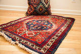 Geometric blue medallion and bold red field of a circa 1940 Northwest Persian rug.