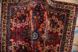 A soft fold in a vintage Sarouk rug reveals its dense pile and red and blue floral motifs.