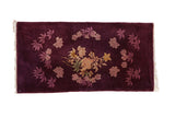 Antique Art Deco rug runner with floral bouquets on a deeply saturated aubergine ground.