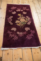 Angled perspective of an Art Deco rug runner with floral bouquets on a rich aubergine ground.