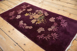 Tattered end fringe and plush aubergine wool pile on an antique Art Deco floral rug.