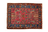 Vintage Persian Lilihan rug with a geometric floral pattern on a raspberry red field with a blue border.