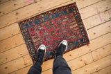Vintage Lilihan Persian rug mat with raspberry red field seen from an overhead perspective.
