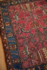 Corner view of a vintage Lilihan rug showing its raspberry red field and sapphire blue floral border.