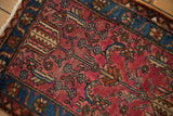 Close-up of geometric blossoms and scrolling vines on the textured pile of a vintage Lilihan.