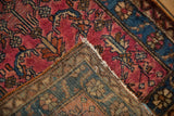 Corner of a vintage Persian rug showing its hand-knotted foundation and raspberry red pile.