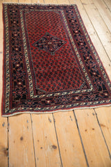 Angled view of a vintage Engelas rug, showing the navy blue diamond medallion on a cherry red boteh field.