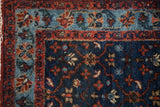 Finely woven corner of a vintage Bibikabad rug with floral motifs in indigo, sky blue, and red.