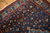 Finely woven floral trellis pattern on the indigo blue and brick red corner of a vintage rug.