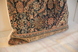 Edge of a vintage Persian Fereghan pillow, displaying its navy, rust, and ivory pattern.