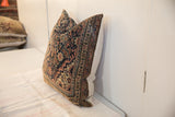 Hand-knotted vintage rug fragment pillow corner with faded navy and earth tone pattern.