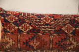 Geometric hand-knotted patterns in rich reds, deep blues, and tan on an antique Turkmen pillow.