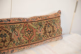Close-up of vintage Fereghan pillow with aged floral motifs in muted coral, olive, and dark tones.