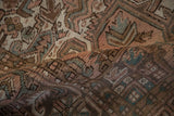 Distressed vintage Mehrivan carpet pile, showing geometric patterns and soft blush, green hues.