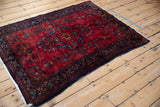 Angled view of a vintage Persian Lilihan rug showing the soft sheen on its red floral pile.