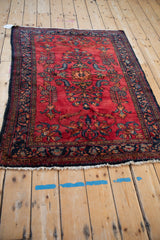 Angled view of a vintage Lilihan rug, showing its curvilinear floral design on a cherry red field.
