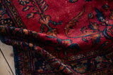 The pliable, soft wool pile of a vintage Lilihan rug in cherry red and deep navy.