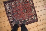Overhead view of the vintage Malayer rug's brick red lattice and indigo pawn border.