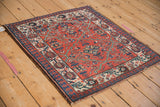 A vintage Persian Malayer rug with a brick red floral lattice design, viewed from an angle.