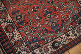 Corner detail of a vintage Malayer rug showing its brick red lattice and ivory pawn border.
