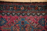 Geometric border and raspberry red pile of a vintage Mehriban rug, showing its soft dye halo effect.