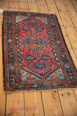 Angled perspective of a vintage Persian Mehriban rug with a stepped medallion in varied red and blue tones.