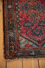 Detail of scattered bird motifs and geometric borders on a vintage raspberry red Persian rug.