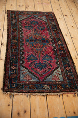 Angled view of a vintage Mehriban rug showing color variation in its raspberry red and blue pattern.