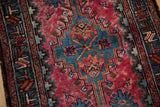 Vintage Persian rug with a blue stepped medallion and scattered birds on a varied raspberry red field.