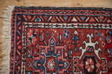A vintage Karaja rug corner with hand-knotted pile, ivory fringe, and intact dark blue side cord.