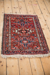 Angled view of a vintage Persian Karaja rug with a central geometric medallion in red and blue.