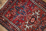 Corner view of a vintage Karaja rug with geometric pile in brick red, denim blue, and ivory.