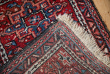 A vintage Karaja rug's corner turned over, revealing the hand-knotted weave and pile.