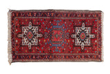 Vintage Karaja rug runner with three geometric hook and latch medallions on a brick red field.