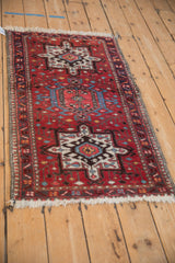 Angled view of a vintage Karaja runner displaying three geometric medallions on a brick red field.